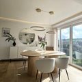 Oval wood dining table with slatted base and four white boucle dining chairs in a modern room.