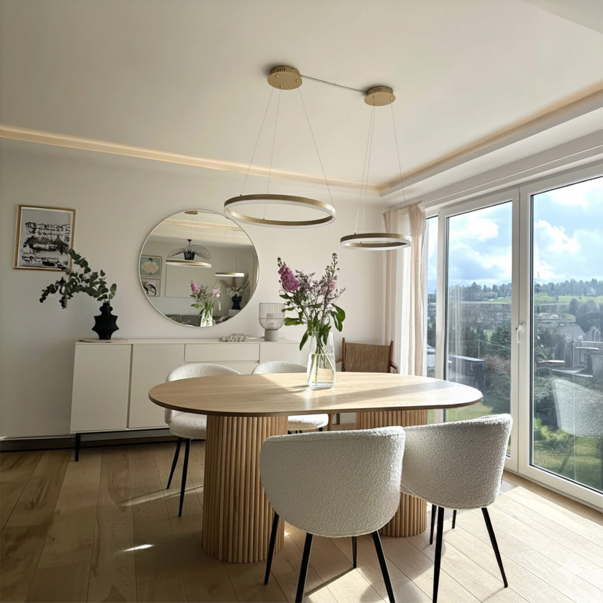 Oval wood dining table with slatted base and four white boucle dining chairs in a modern room.