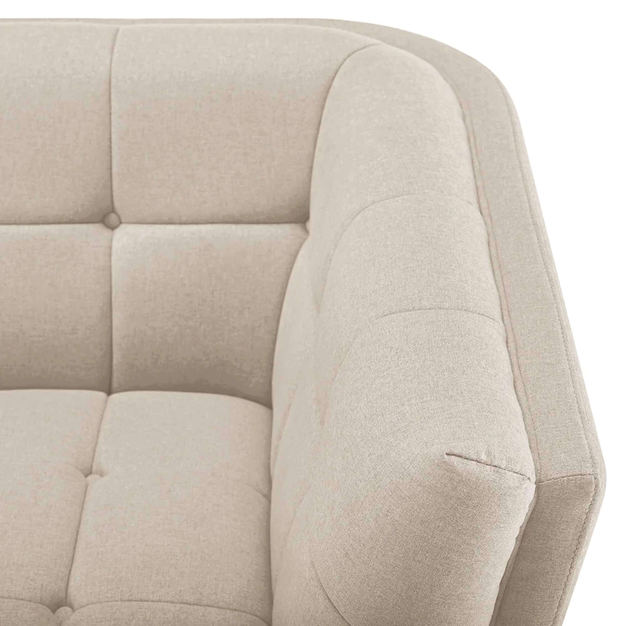 Close-up detail of the corner and armrest of a light beige tufted sofa or armchair, showcasing the fabric texture and square button tufting.