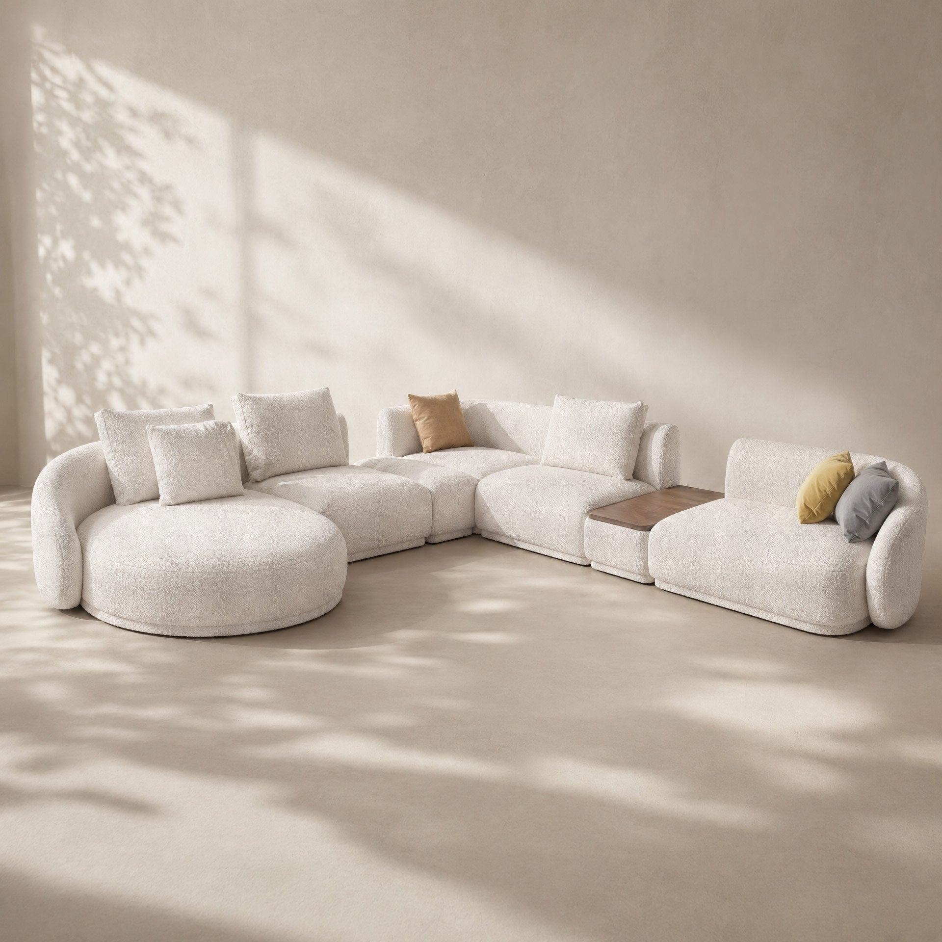 Modern white sectional sofa with cushions in a minimalistic room with sunlight filtering through.