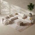 Modern beige sectional sofa in a minimalistic living room with a plant and rug.