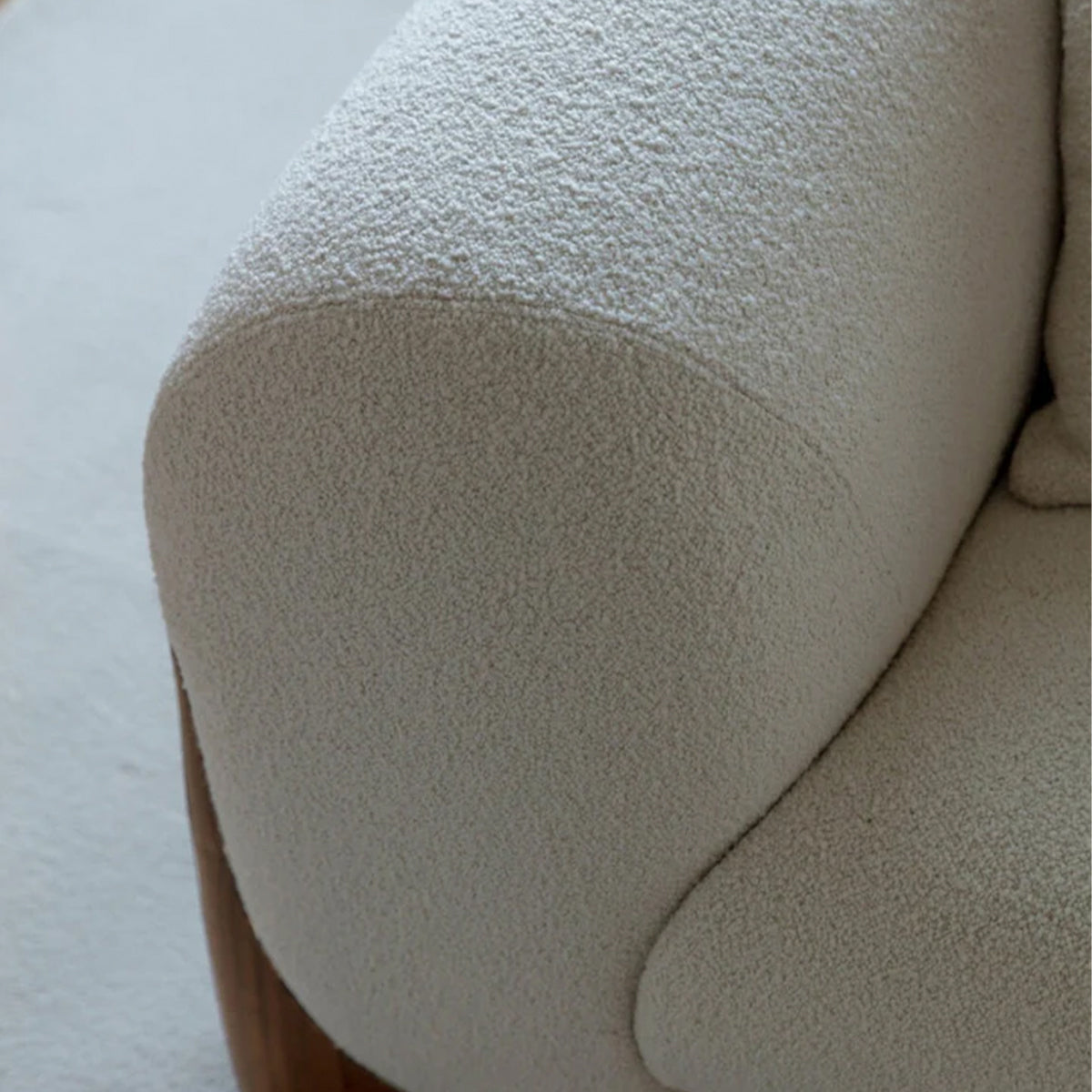 A close-up view showing the texture of the white bouclé fabric on the curved armrest of the Harper sofa.