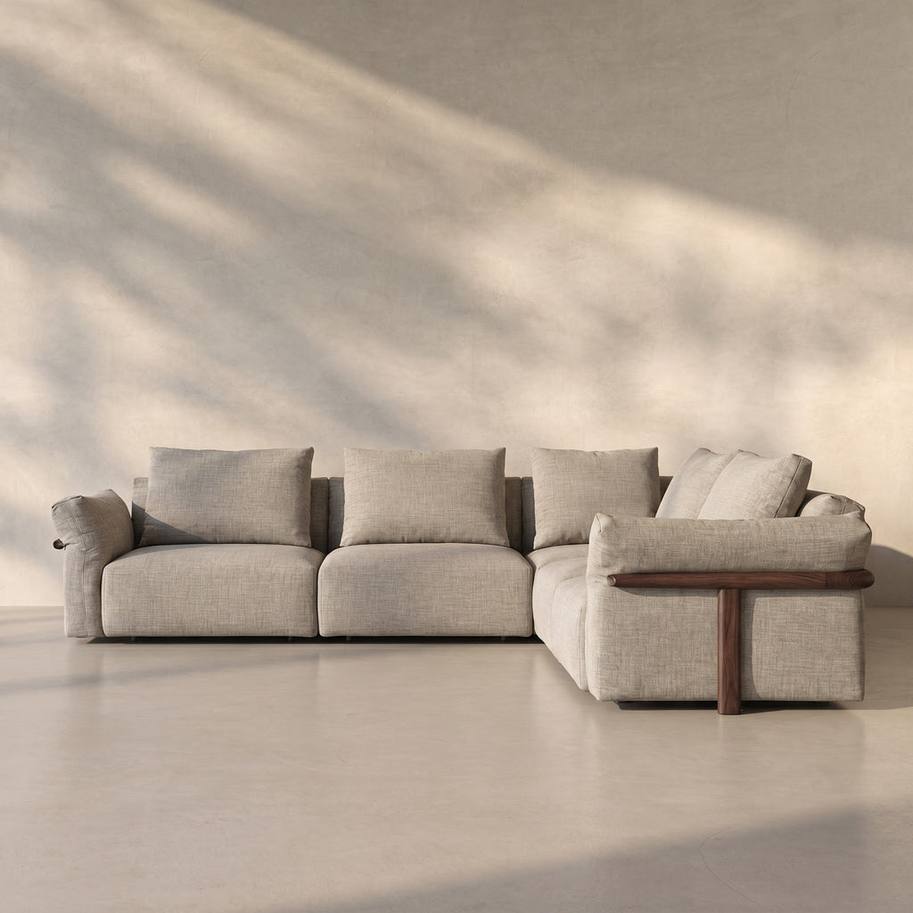 Gray sectional sofa in a room with soft lighting and shadows on the wall.