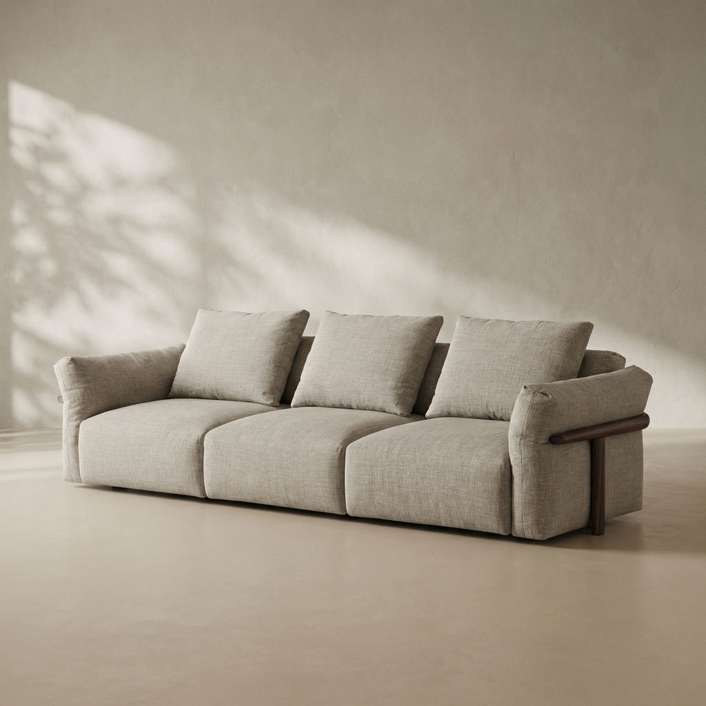 Beige sofa with wooden armrests in a minimalistic room with sunlight casting shadows on the wall.
