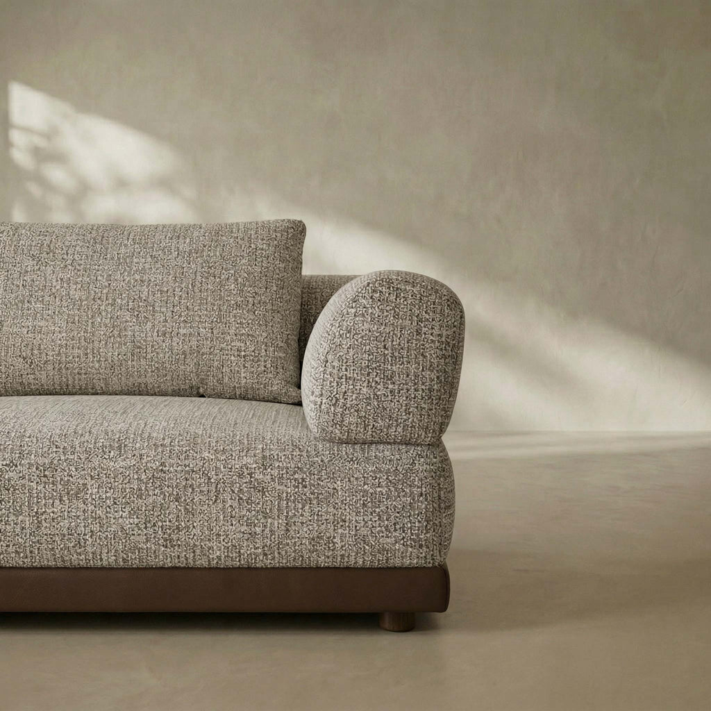 Gray textured sofa against a beige wall with soft shadows