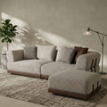 Gray sectional sofa with patterned cushions in a room with a plant and lamp.