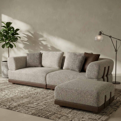Gray sectional sofa with patterned cushions in a room with a plant and lamp.