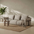 Beige sofa in a room with a plant and small table