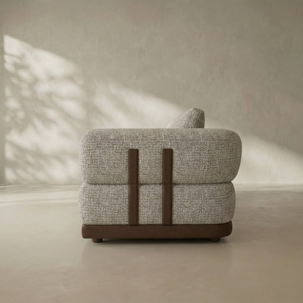 Gray upholstered chair with brown accents in a minimalistic setting