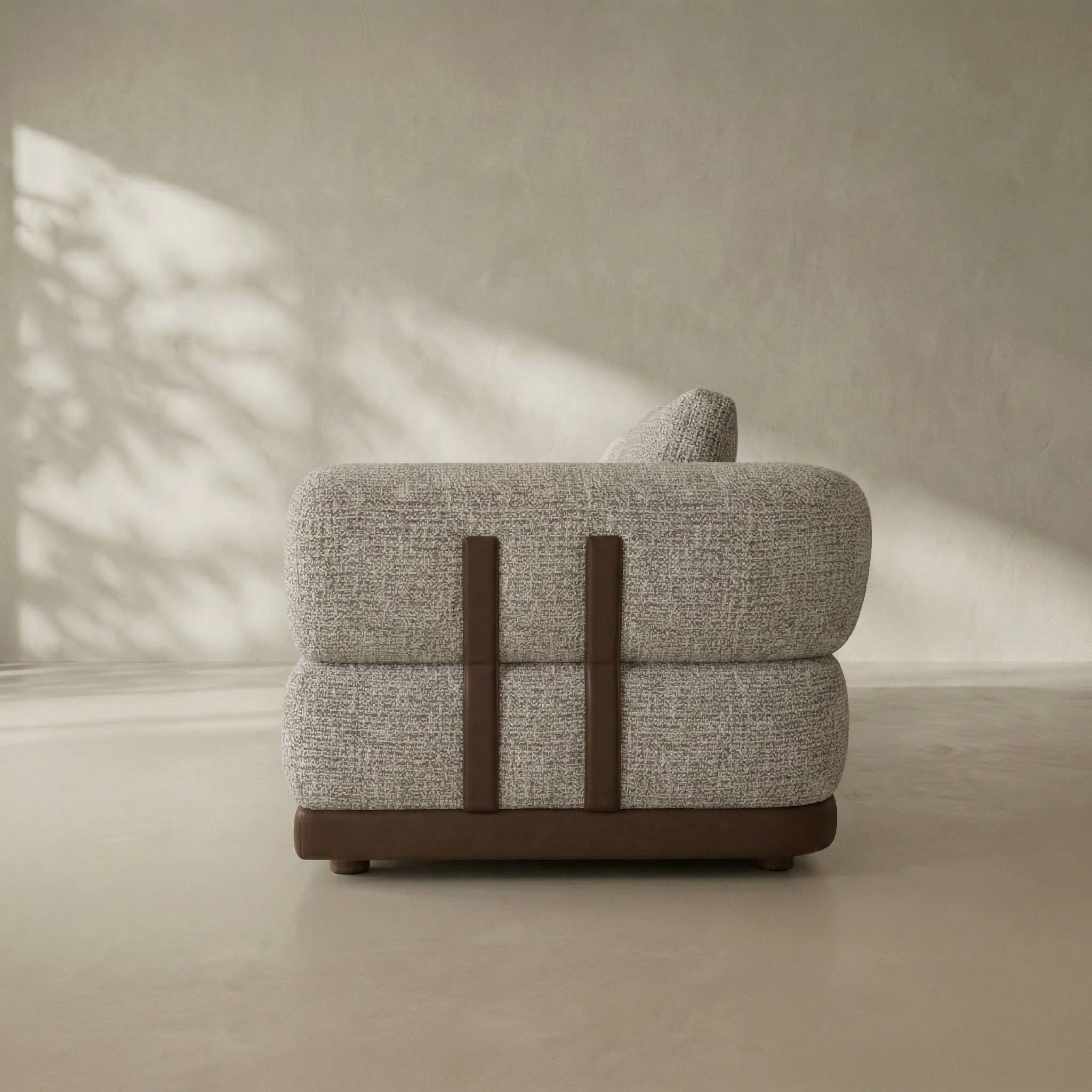Gray upholstered chair with brown accents in a minimalistic setting