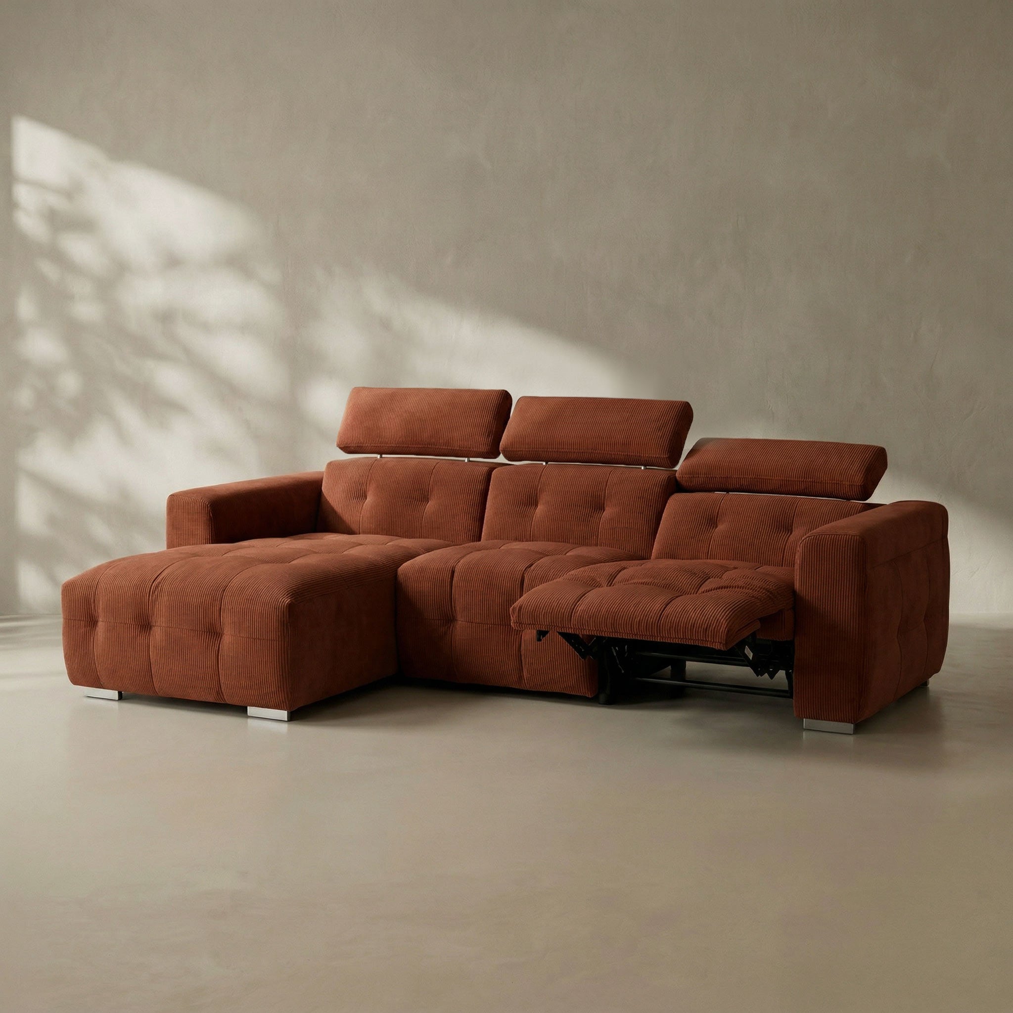 Brown sectional sofa in a minimalistic room with sunlight casting shadows on the wall.