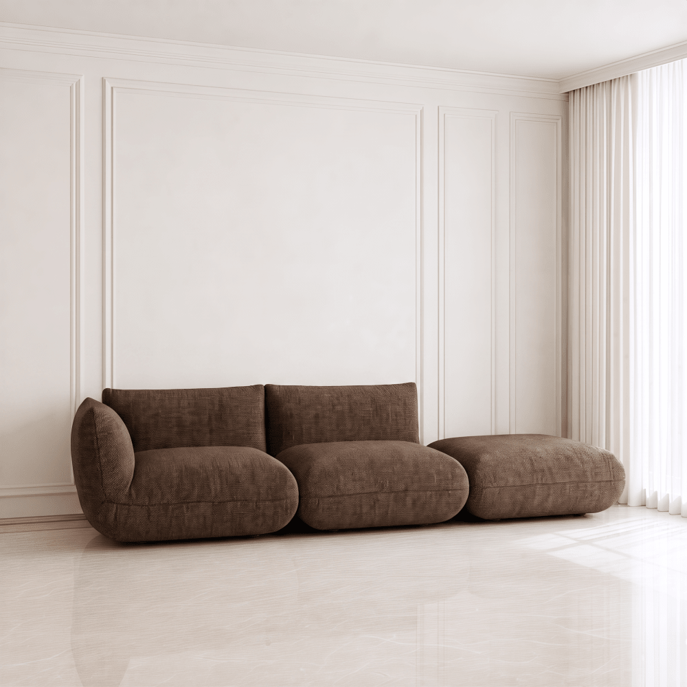 A modern three-seater sofa in a dark brown textured fabric, styled in a minimalist room with white paneled walls and a light marble floor.