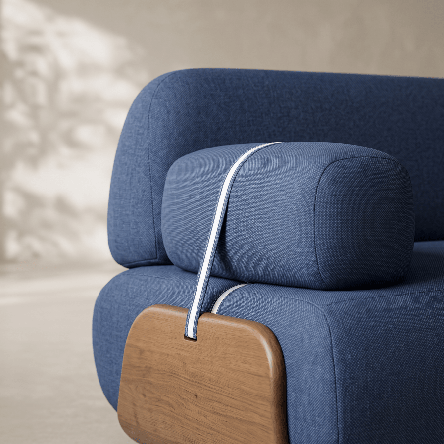 Close-up of a blue upholstered armchair with a matching headrest, a white piping accent, and a curved light wood armrest.