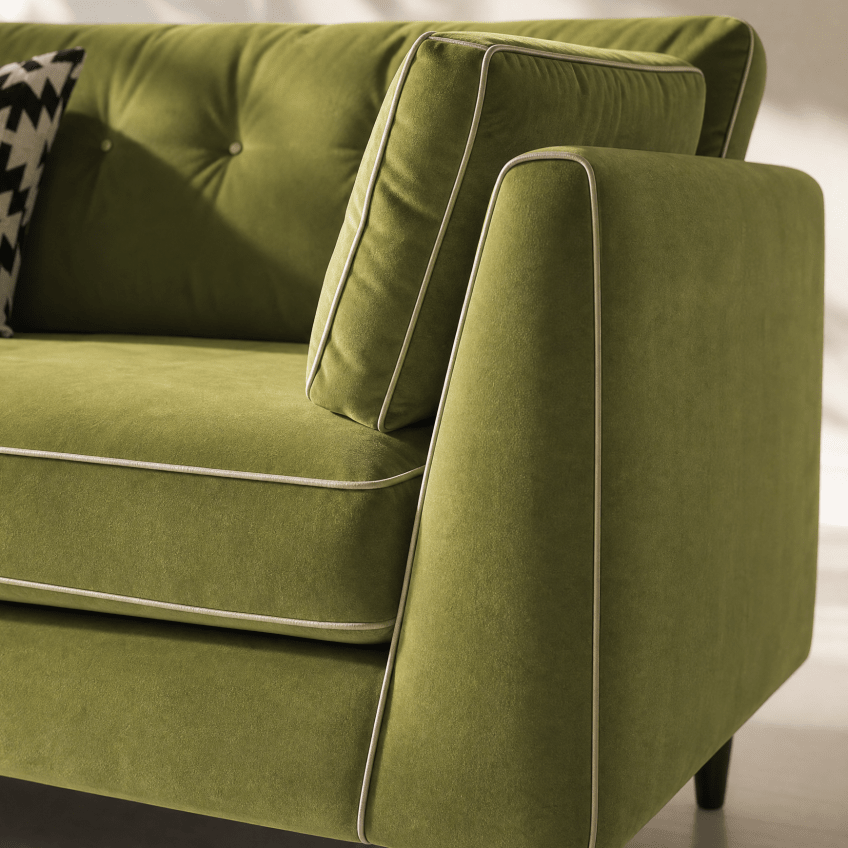 Close-up of an olive green velvet sofa with white contrast piping, showing the tufted back cushion, armrest, and seat cushion.